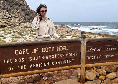 Tourist standing by Cape of Good Hope sign with ocean and cliffs