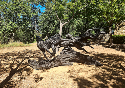 Wildlife sculpture of running animals in a shaded park setting
